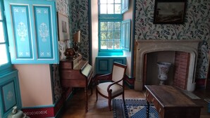 A room with a fireplace, a window, a dog, and a chair. - Château-l'Evêque in Périgord (Château-l'Évêque)