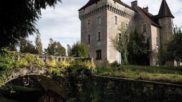 Un edificio histórico de piedra con una torre destacada y un puente en primer plano.