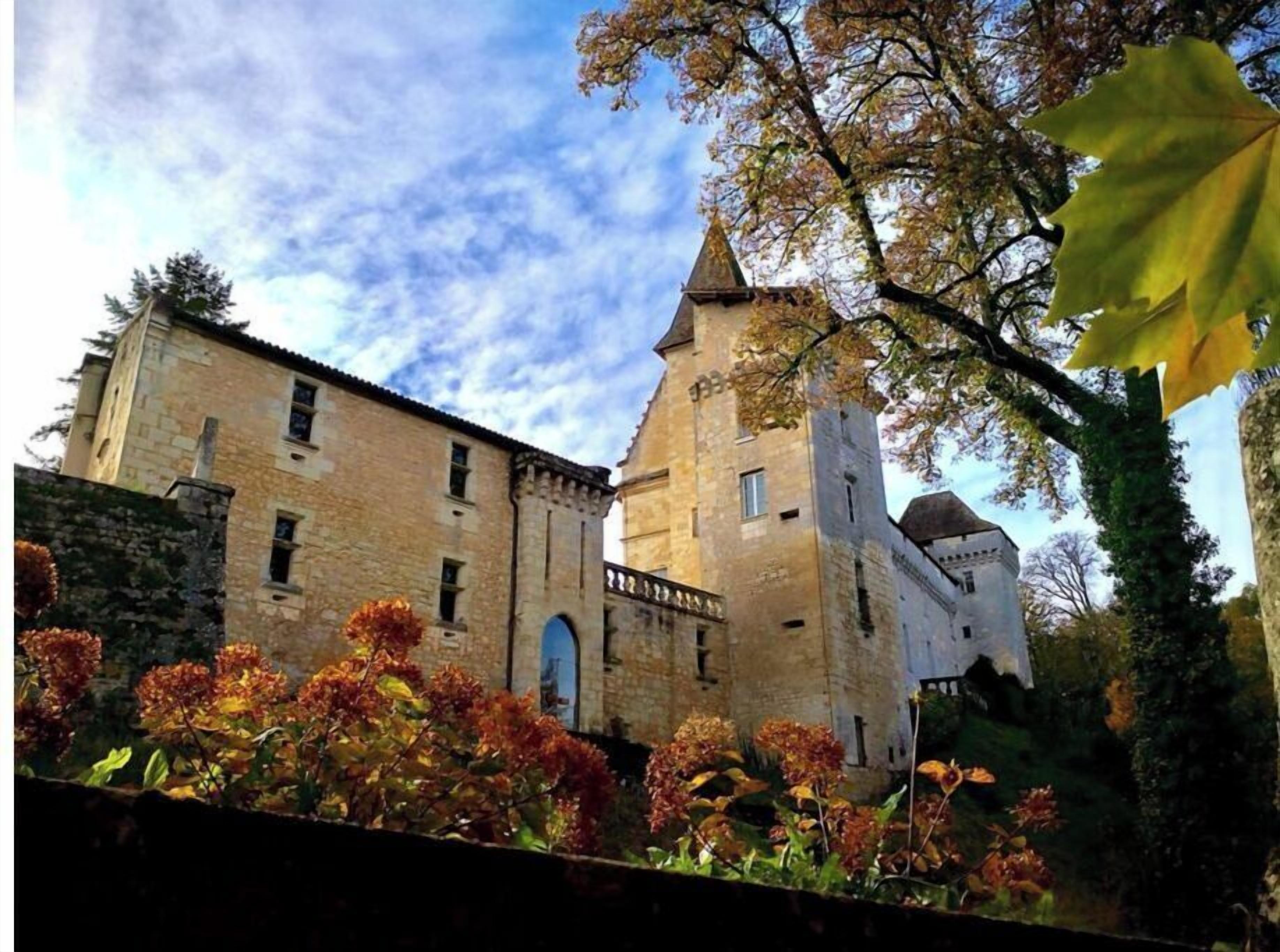 Un edificio histórico de piedra con una torre destacada y ventanas de arco.