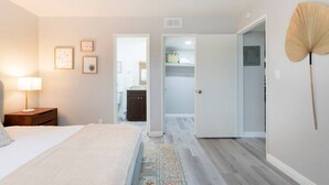 A bedroom with a bed, nightstand, and wall art. There is a hallway leading to a bathroom and a closet. - DT Alhambra 2Br/2Ba with King bed + EV Charger (Alhambra)