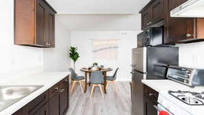 A compact kitchen with a dining area, featuring a refrigerator, microwave, stove, and a small table with chairs. - DT Alhambra 2Br/2Ba with King bed + EV Charger (Alhambra)