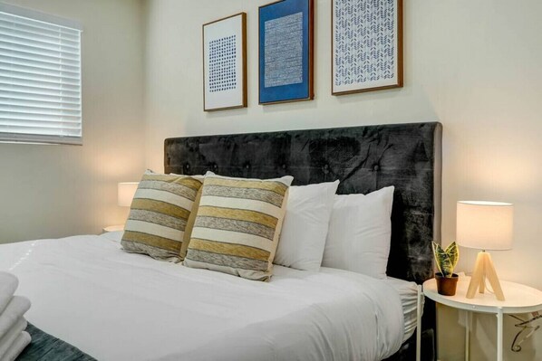 A neatly made bed with striped pillows, a dark headboard, and framed artwork on the wall.