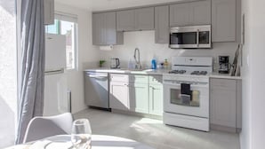 A modern kitchen with grey cabinets, a stainless steel microwave, a white stove, and a dishwasher.