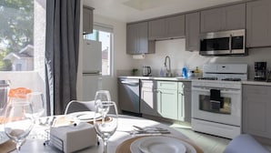 A modern kitchen with grey cabinets, a stainless steel microwave, and a white oven.