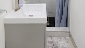 A modern bathroom with a white sink, a mirror, and a shower with a curtain.