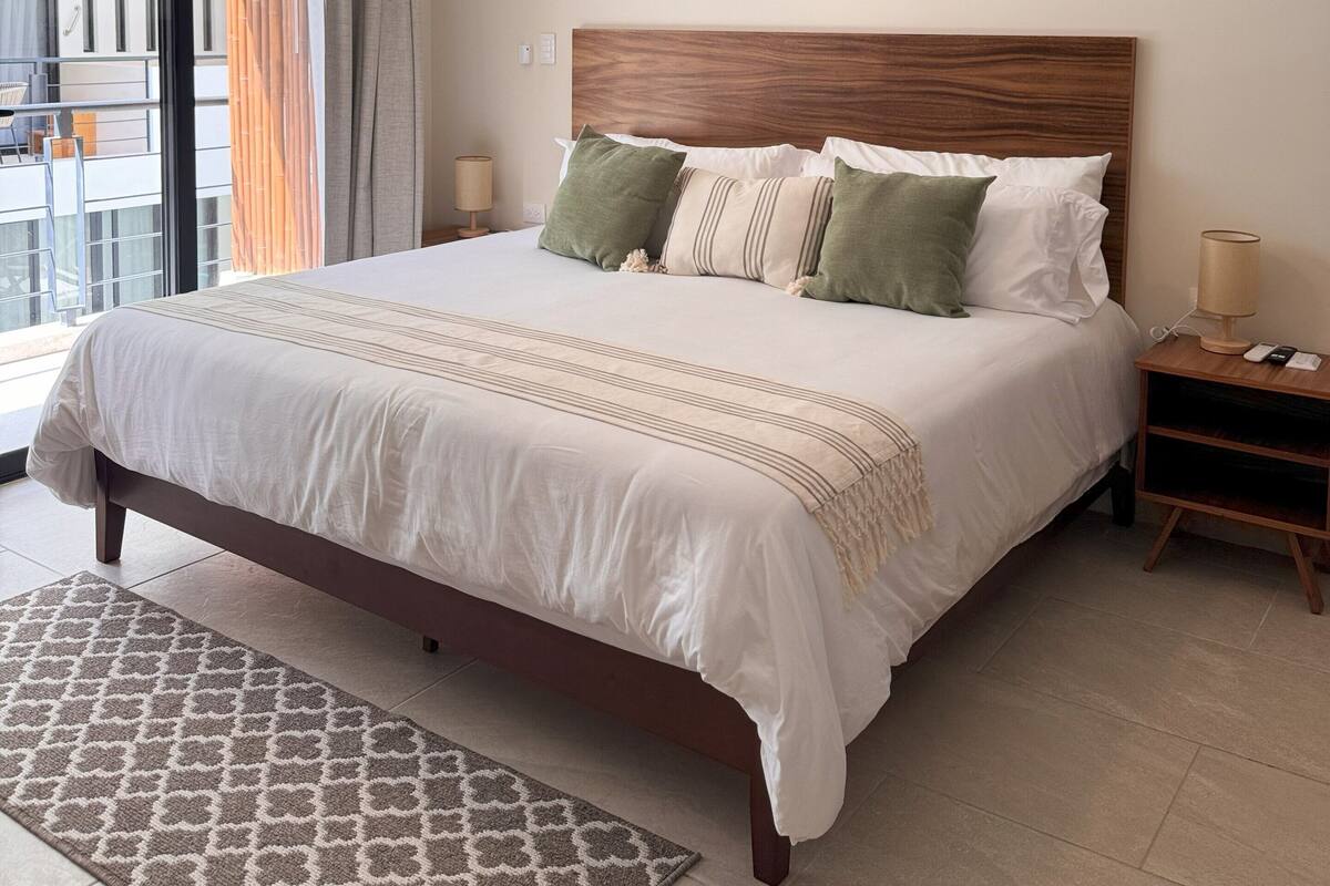 Een hotelkamer met een groot bed, een plafondventilator, een decoratieve wandversiering en een airconditioning.