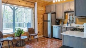 Eine Küche mit Holzwänden, einem Kühlschrank, einem Geschirrspüler und einem Essbereich mit Tisch und Stühlen.