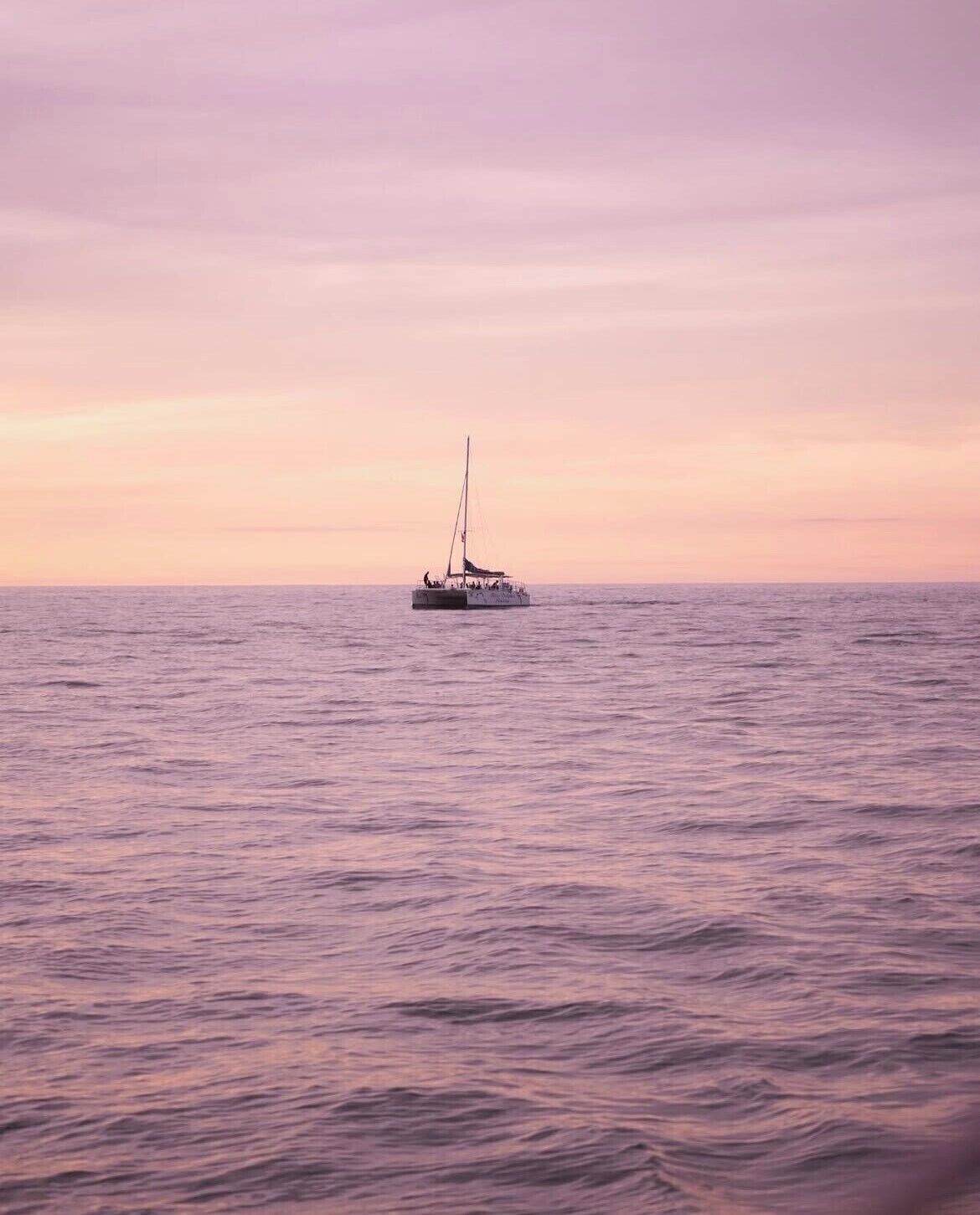 A sailboat on calm waters during sunset.