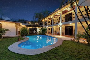 A two-story building with a swimming pool, outdoor lighting, and a starry night sky. - Villas Vibras (Tamarindo)