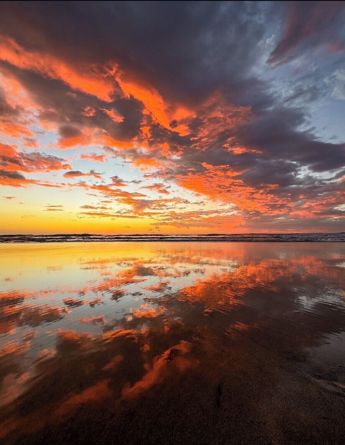 A beach with a sunset reflection on the wet sand.
