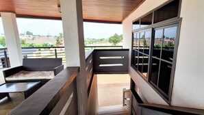 A balcony with a view of the city, a wicker chair, and a small table. - LC Lodge & Event Centre (Kumasi)
