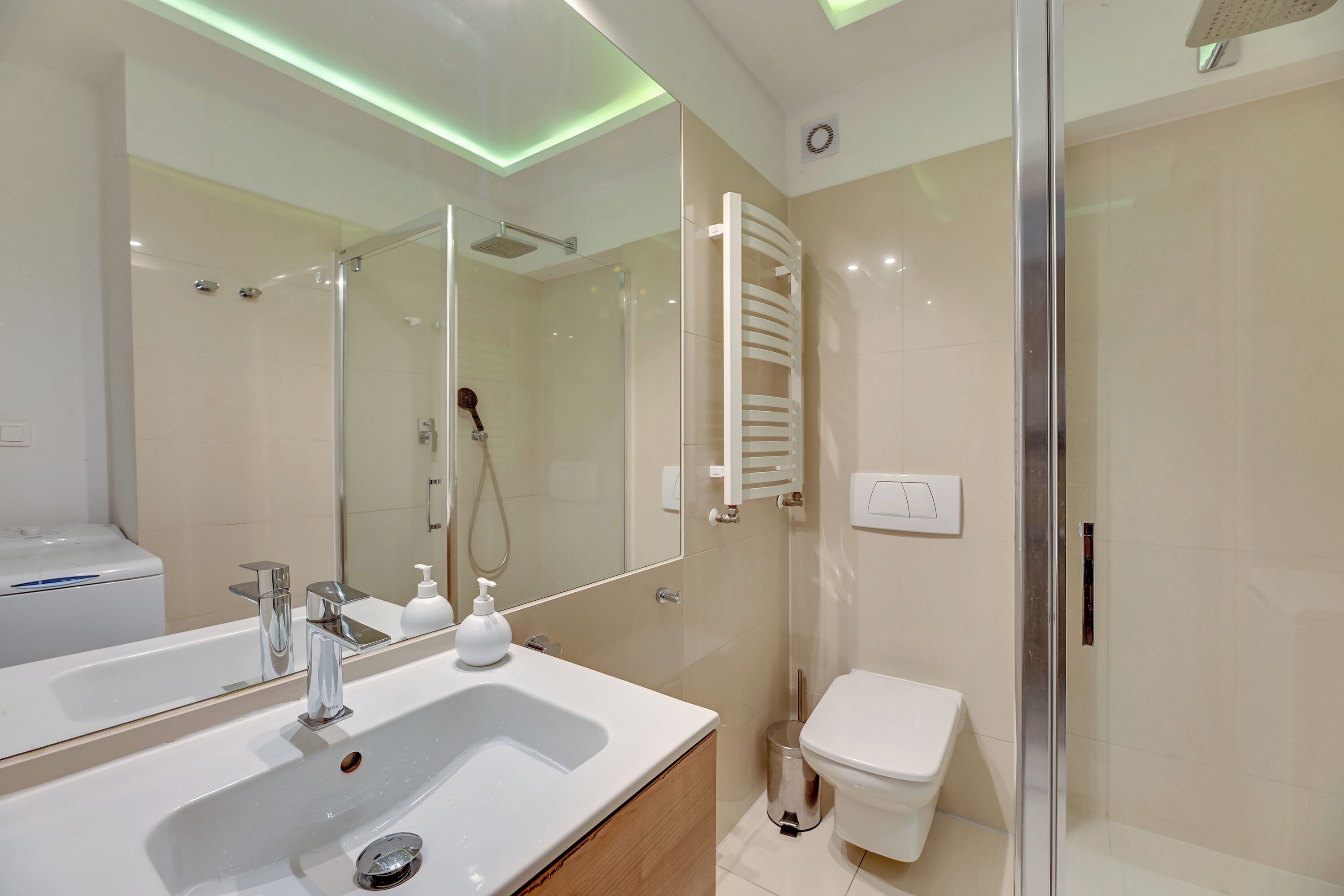 Een moderne badkamer met een grote spiegel, een wastafel, toilet en een douchecabine met glazen wanden.