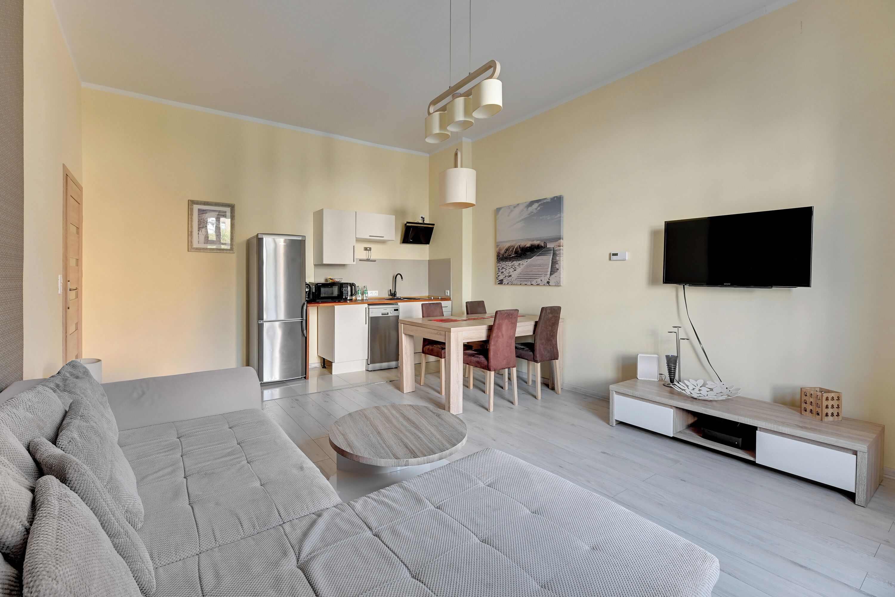 A modern living room with a sofa, dining table, and TV.