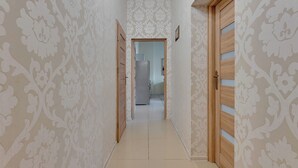 A hallway with patterned wallpaper, wooden doors, and a tiled floor. - Bryza by Grand Apartments (Sopot)