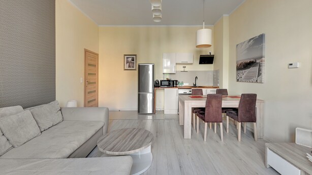 A modern living room with a sofa, a round coffee table, and a dining area with chairs and a table. - Bryza by Grand Apartments (Sopot)