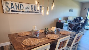 A dining table set with coasters, a cooler, and condiments. - Direct Beachfront Sea Oats Condo in Cocoa Beach (Cocoa Beach)