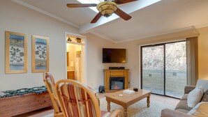 Un salón acogedor con chimenea, televisor y un amplio ventanal que ofrece vistas al exterior.