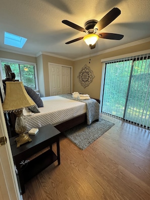 Relax in a serene bedroom with a large bed, ceiling fan, and sliding glass door leading to an outdoor area.