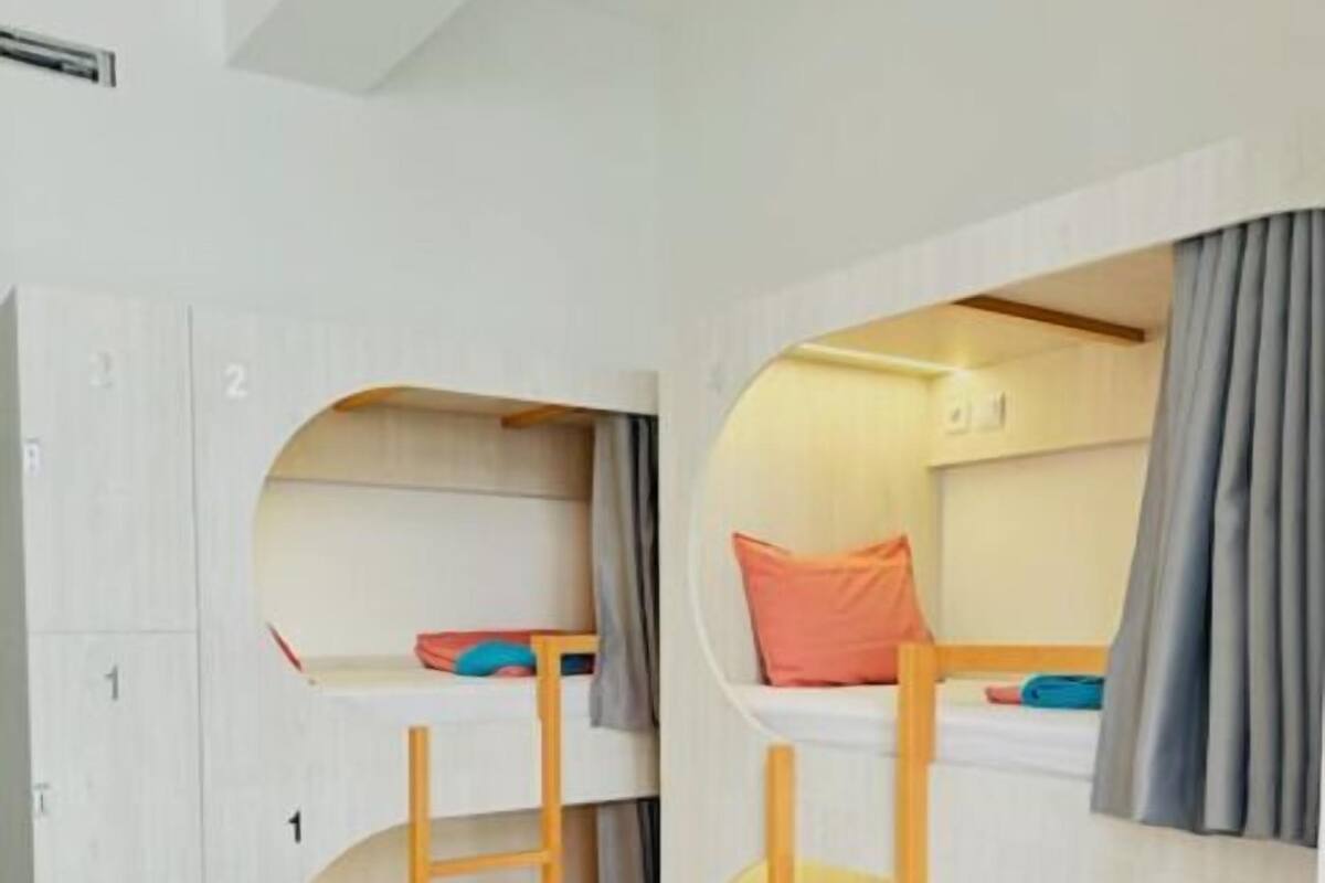 A room with bunk beds, each with a ladder and pillows.