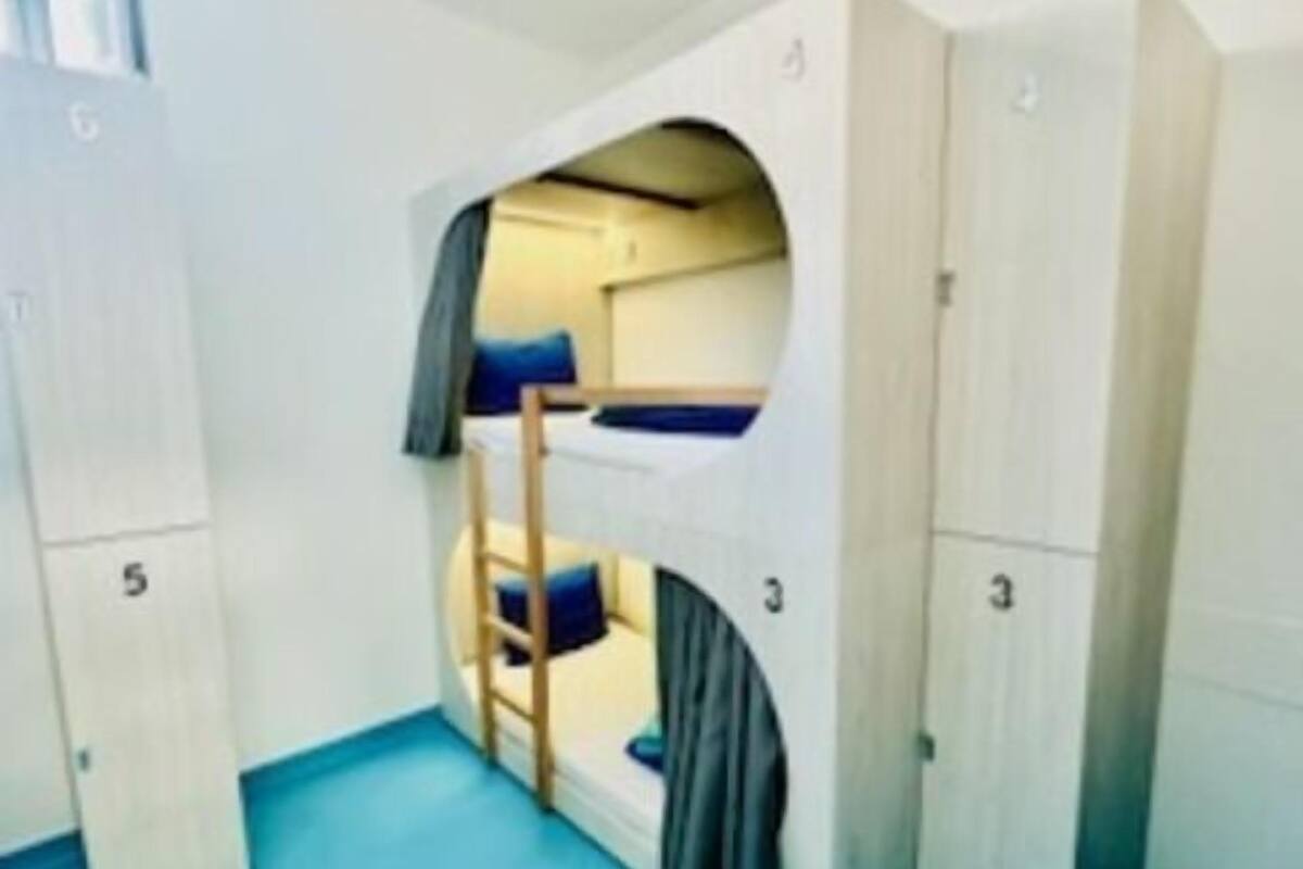 A bunk bed room with a window, a desk, and a chair.
