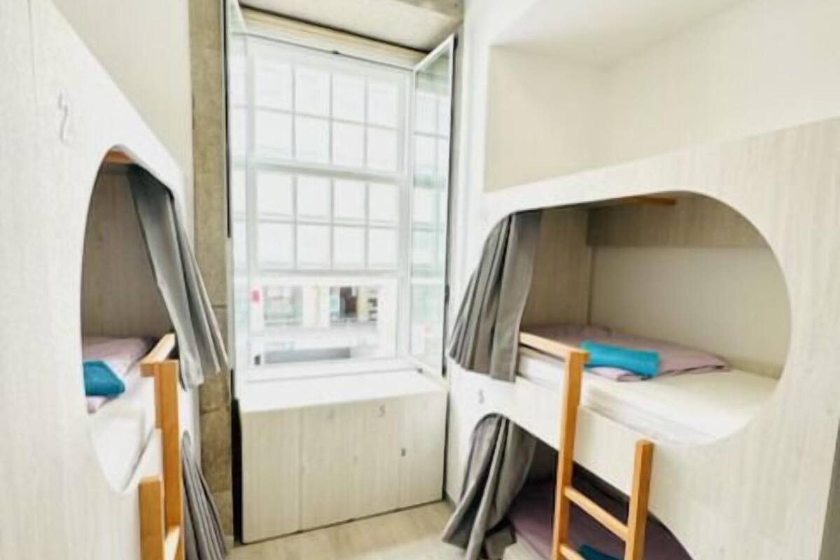 A compact room with bunk beds, a window, and a small desk.