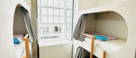 Habitación pequeña con literas, una ventana y un escritorio.