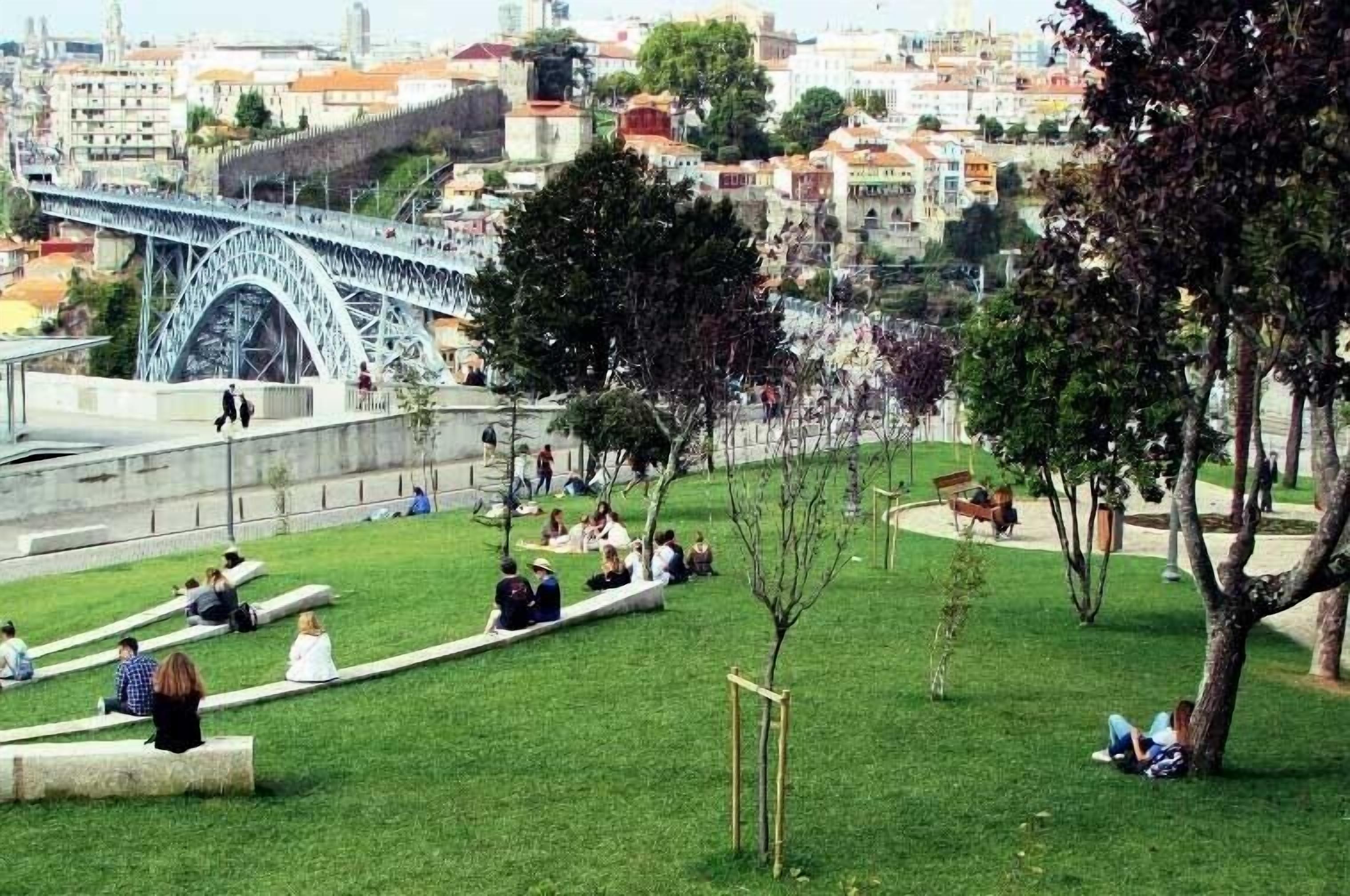 Un parque con un puente, zonas de descanso y árboles.