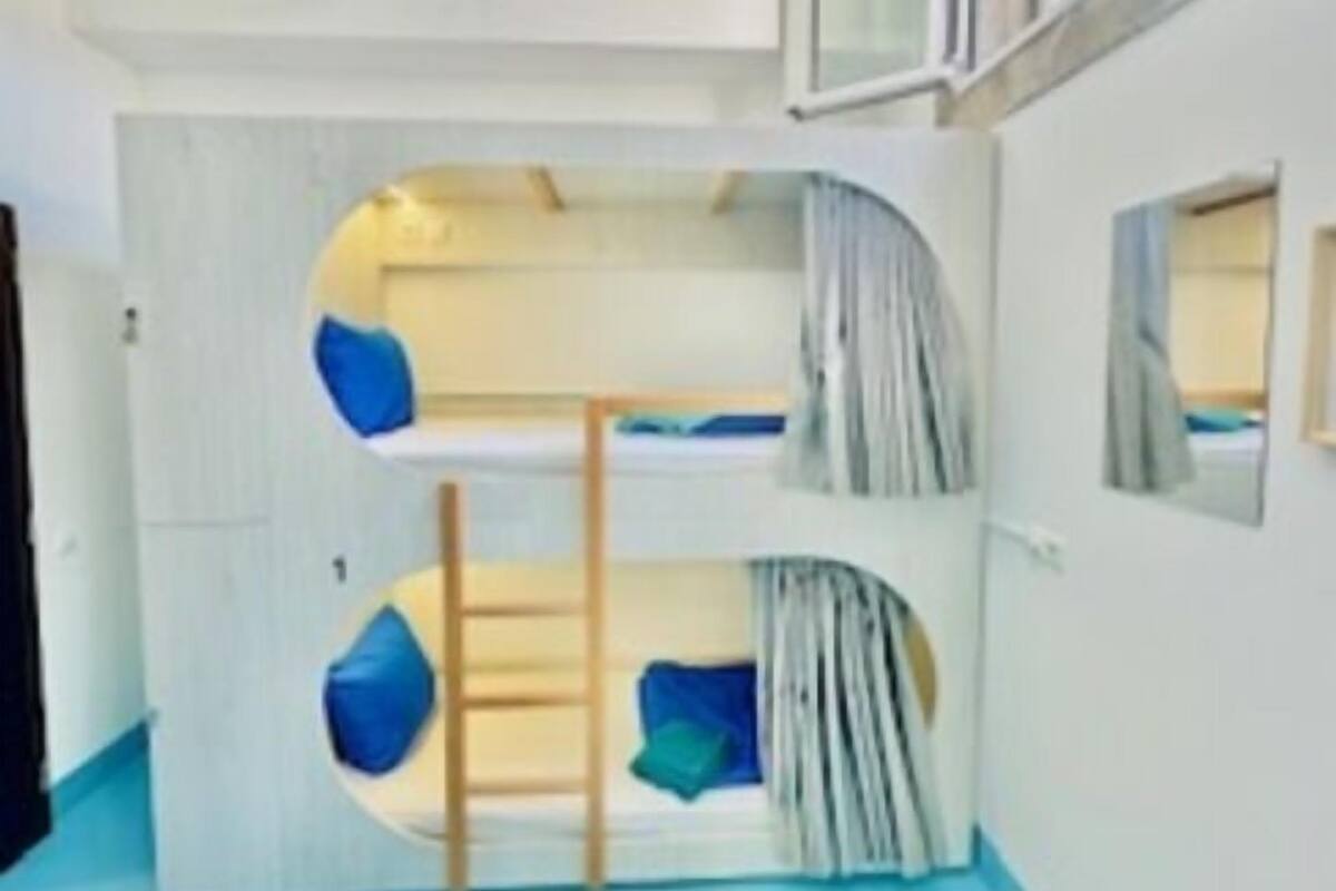 A bunk bed room with a ladder, a small window, and a mirror on the wall.