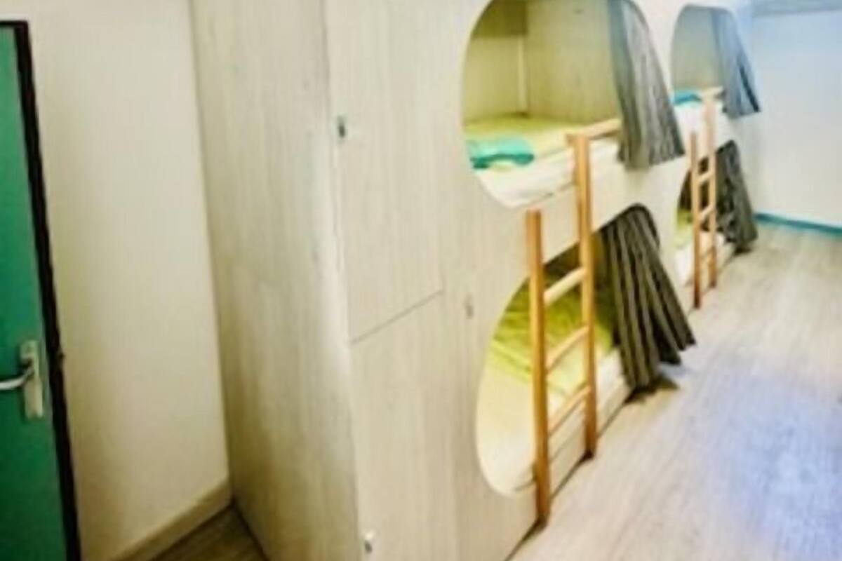 A room with bunk beds, a wardrobe, and a small window.
