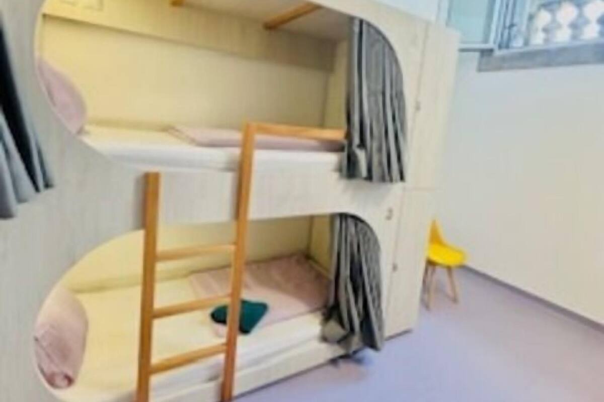 A bunk bed room with a window and a yellow chair.