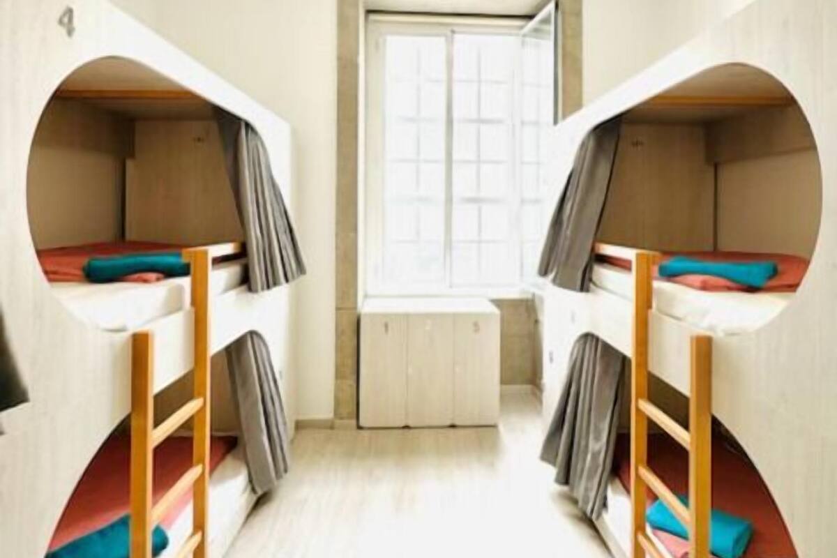 A room with two bunk beds, a window, and a door.