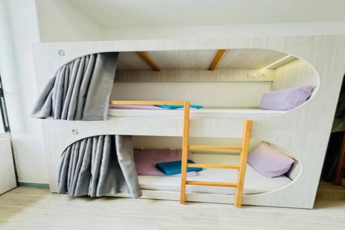 A bunk bed with a ladder, curtains, and pillows.