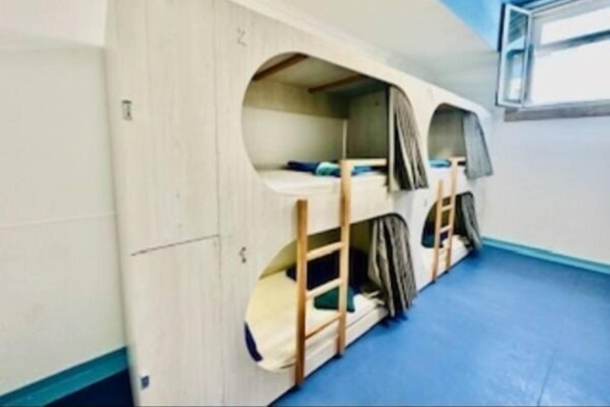 A bunk bed room with a blue floor, wooden bunk beds, and a window.