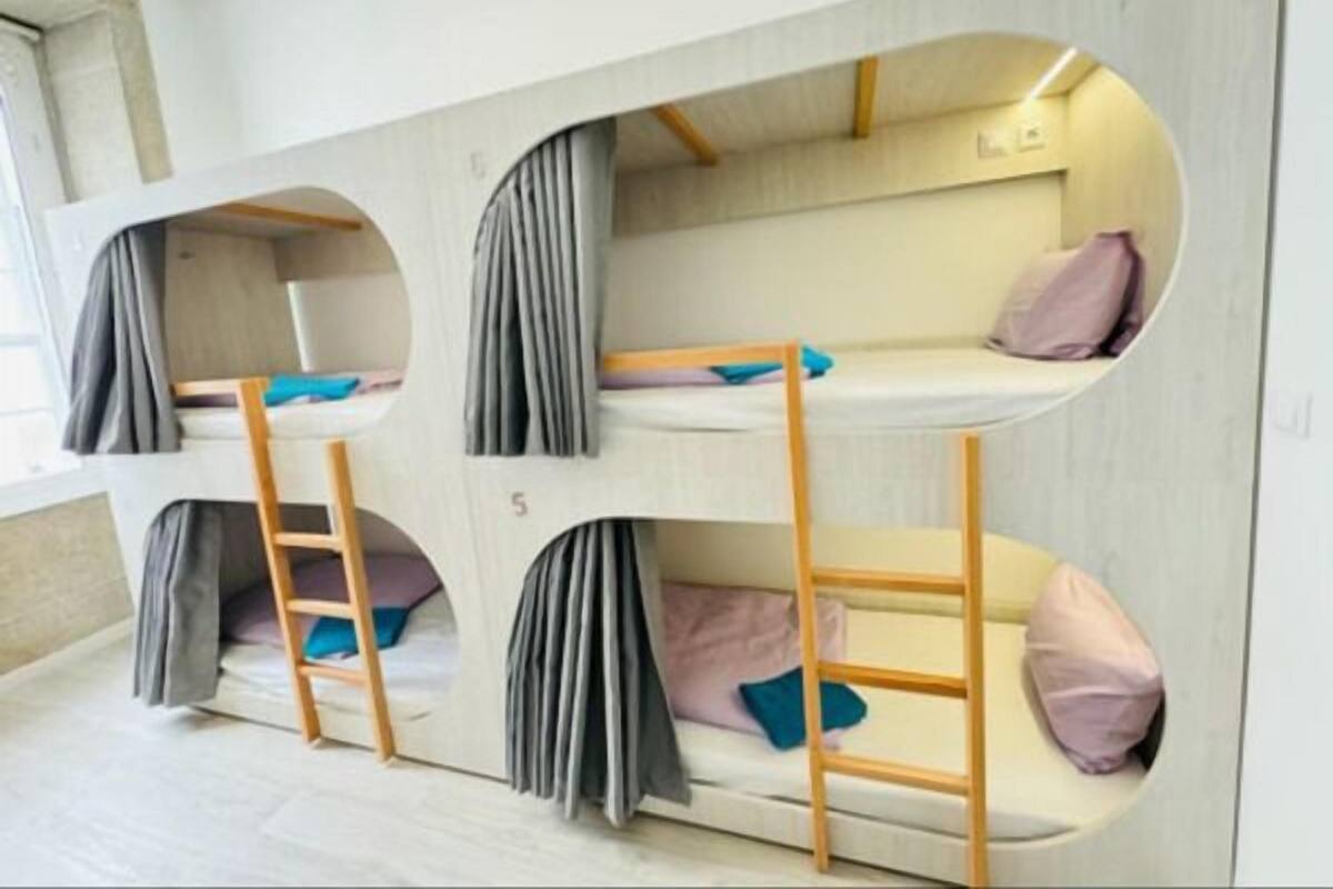 A bunk bed room with three levels, each with a ladder and pillows.