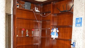 Een houten receptiebalie met een telefoon, een klein plankje met decoratieve objecten, en een blauw bord dat een rookruimte aangeeft.