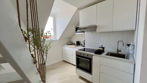 Une cuisine moderne avec des meubles blancs, un four encastré et un évier en acier inoxydable.
