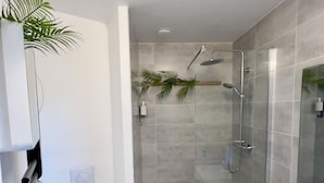 Une salle de bain moderne dotée d’une douche à parois de verre, de toilettes et d’un meuble-lavabo avec un miroir.