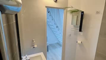 Ein modernes Badezimmer mit Waschbecken, Spiegel und Toilette. Eine Treppe führt in einen anderen Raum.