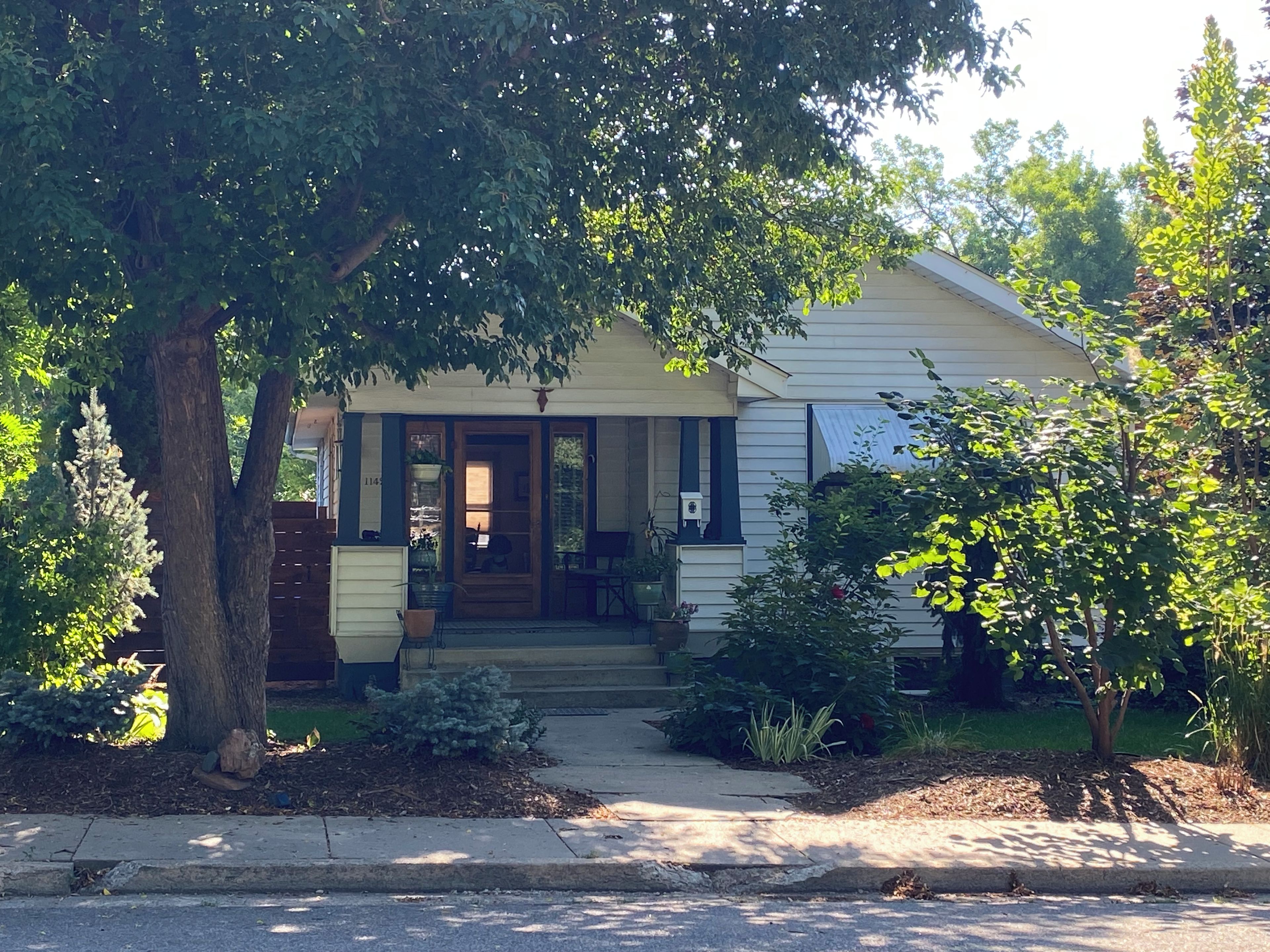 A single-story house with a front porch, a mailbox, and a small garden area.