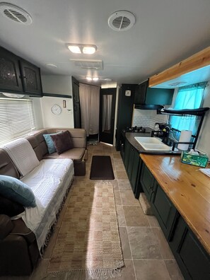 A compact RV interior with a kitchenette, a sofa, and a small rug.
