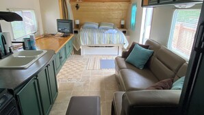 Ein kompaktes Wohnmobil-Interieur mit Küchenzeile, einem Bett, einer Sitzecke und einem kleinen Fernseher.