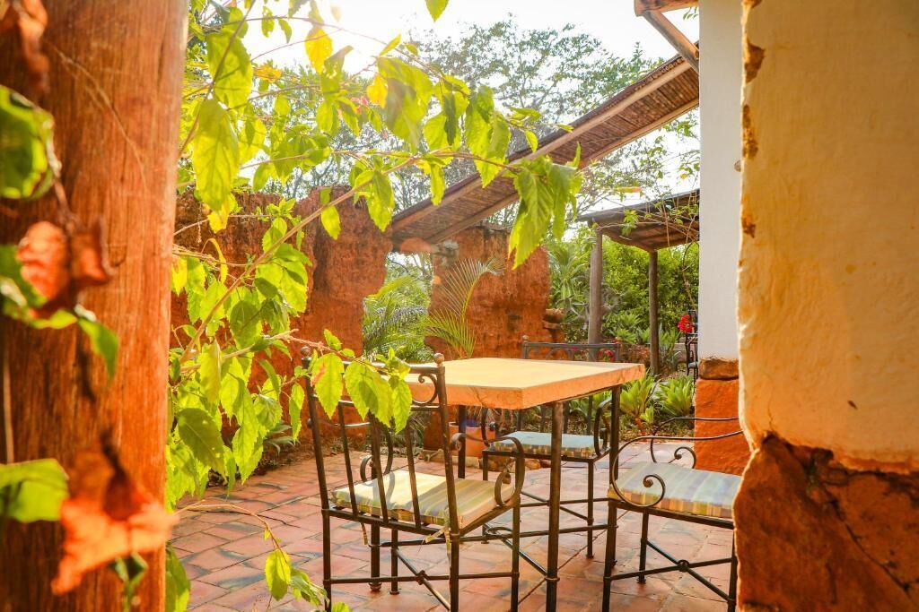Une terrasse extérieure avec une table et des chaises, entourée de verdure et de murs en briques.