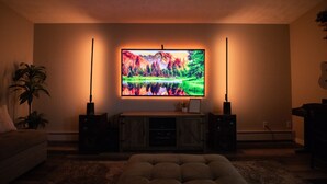 A living room with a flat-screen TV mounted on the wall, a wooden entertainment center, and a plush sofa. - Modern Upstairs Apartment Near Airport, Shopping Centers and Trails Unit #A (Anchorage)