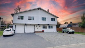 A two-story house with a garage, driveway, and a garden area.