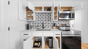 A modern kitchen with white cabinetry, a stainless steel microwave, an oven, and a patterned backsplash. - Charming 2-bedroom house in enchanting Cleveland with AC, WiFi  3219 (Cleveland)