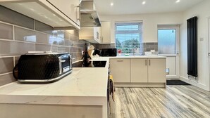 A modern kitchen with a large island, white cabinetry, and a black countertop.