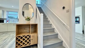 A modern interior with a staircase, a wooden storage unit, and a kitchen area.