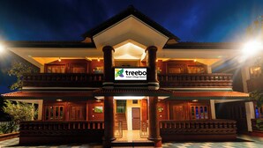 Un edificio tradicional de varios pisos con un letrero que indica Treebo Green Village Resort.
