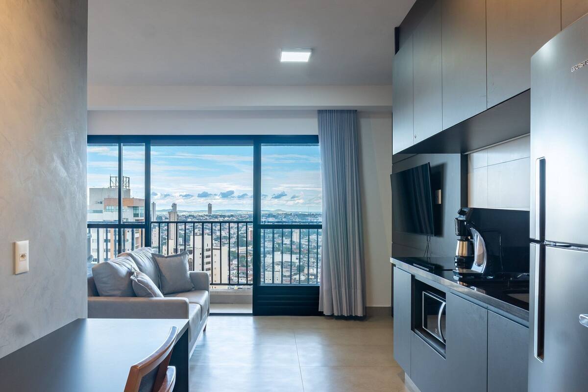 Een modern appartement met balkon, een bank, een eettafel en een keukenhoek.