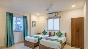 A hotel room with two beds, a wardrobe, a ceiling fan, and an air conditioning unit. - Treebo De Alphabet Gachibowli (Hyderabad)